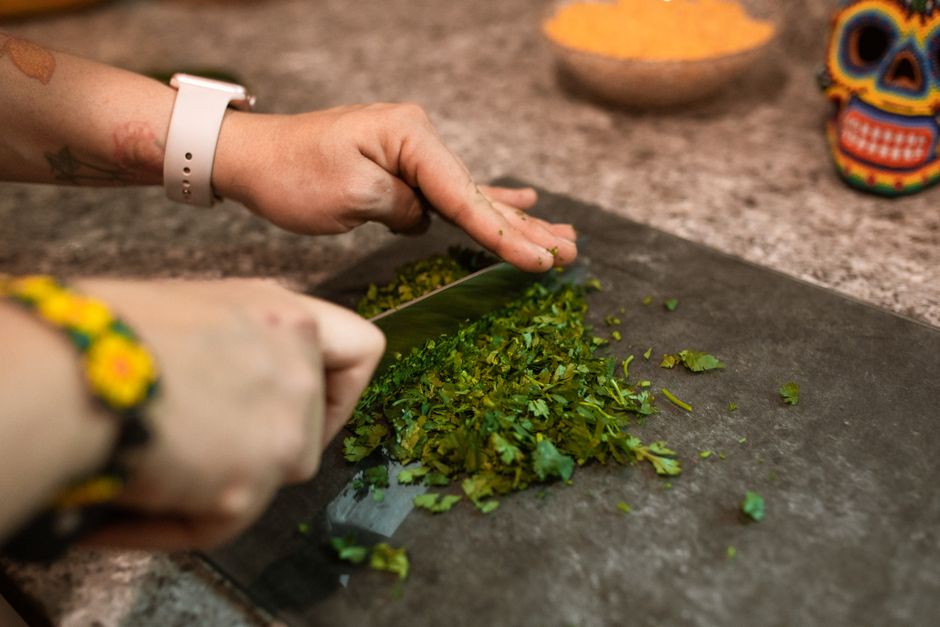 Hands chopping fresh herbs on a cutting board, capturing food preparation process.