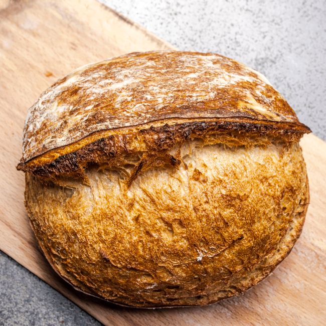 Fresh artisan sourdough bread with a golden crust on a wooden board.